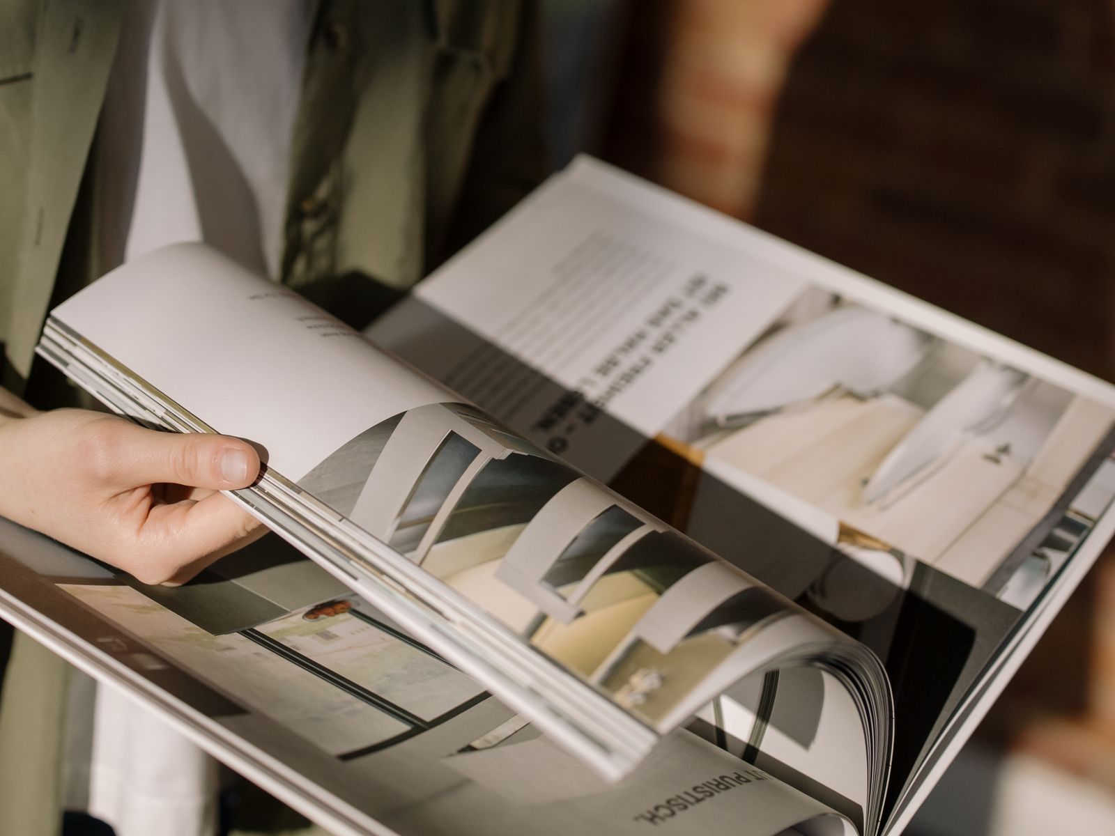 Hands turning the pages of a large-format architecture magazine
