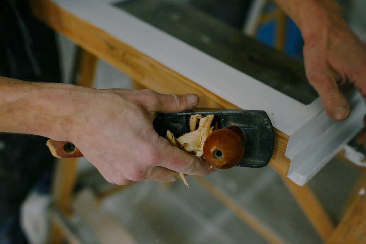 A joiner running a hand plane along a length of timber