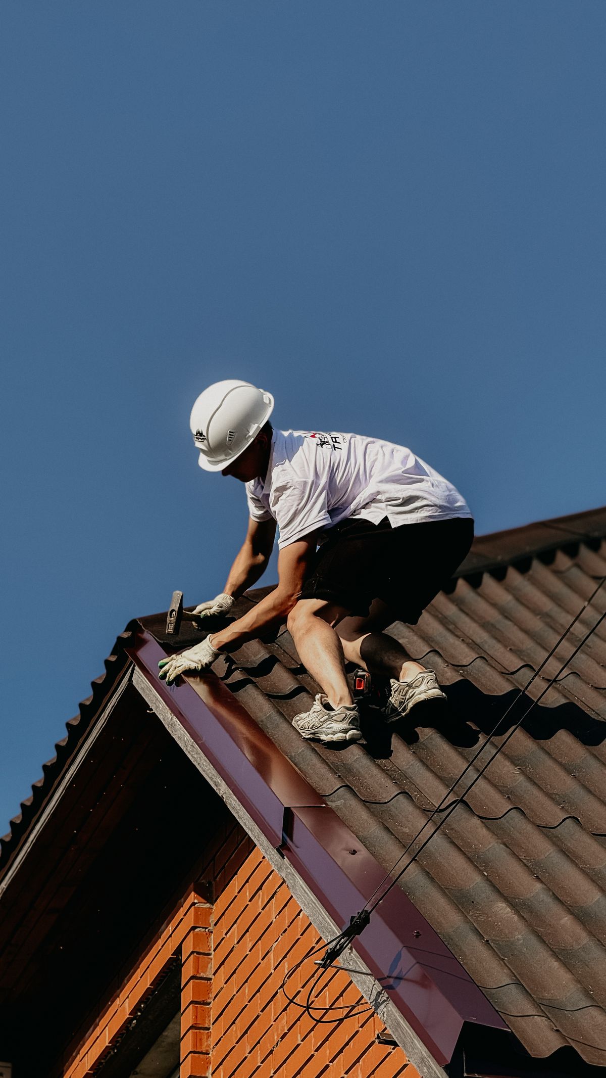 A roofer working across tiles against an open sky